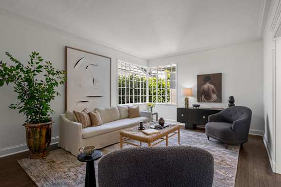 A living room with a couch, chair, and potted plant.