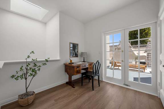 A room with a desk, chair, and a potted plant.