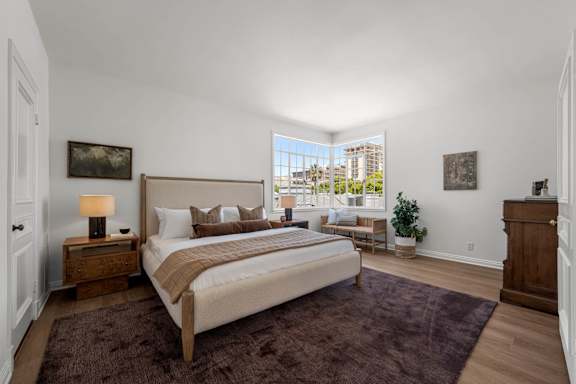 A bedroom with a window overlooking a cityscape.