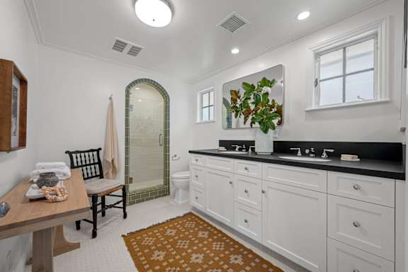 A bathroom with a sink, mirror, and a rug on the floor.