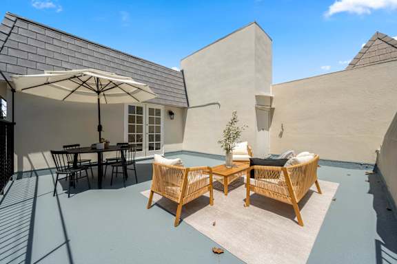 A patio with a table and chairs under an umbrella.