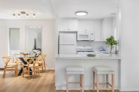 a kitchen and dining room with white cabinets and a white counter top