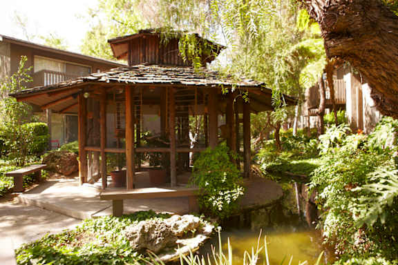 A small wooden pavilion with a tiled roof is surrounded by greenery.at The Aspens South Coast, South Coast Metro, 92504