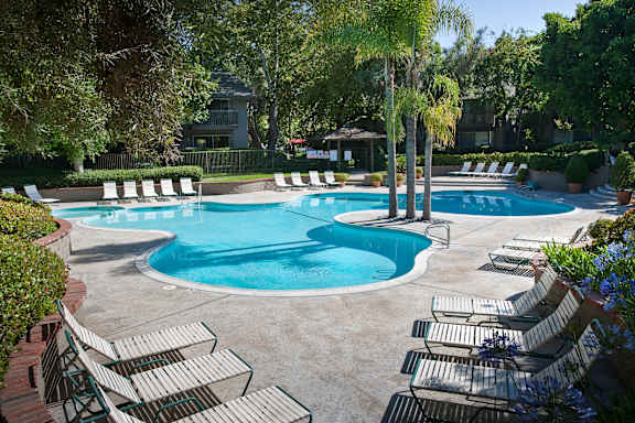 A large swimming pool surrounded by lounge chairs and trees.at The Aspens South Coast, California