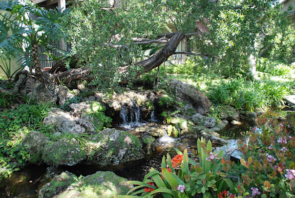 A small waterfall in a garden surrounded by rocks and plants.at The Aspens South Coast, California, 92504
