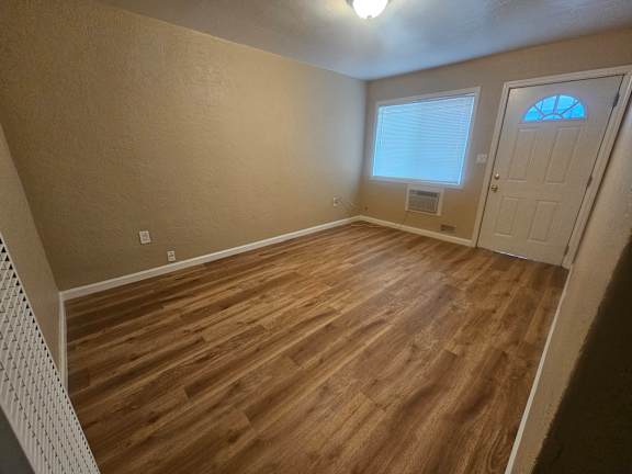 A room with wooden flooring and a door with a window.