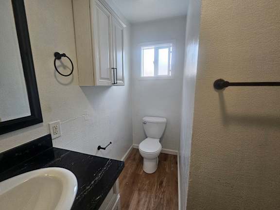 A small bathroom with a toilet, sink, and a window.