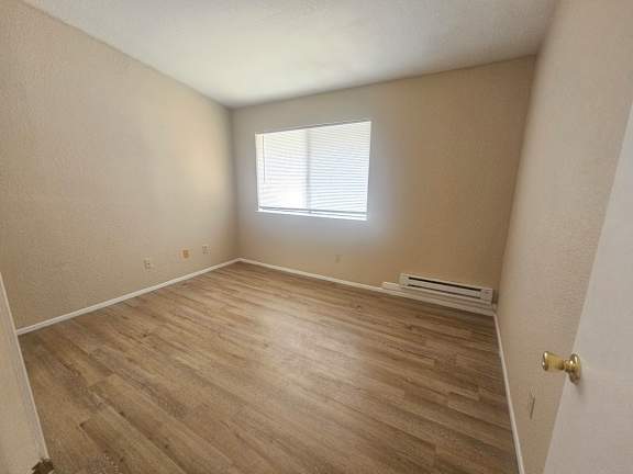 A room with wooden flooring and a window.