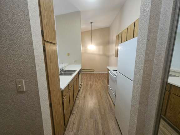 A kitchen with white appliances and wooden cabinets.