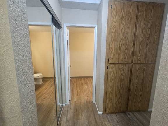 A bathroom with a toilet, a shower with a glass door, and a wooden wardrobe.