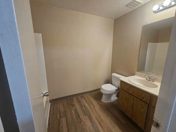 A bathroom with a toilet, sink, and mirror.