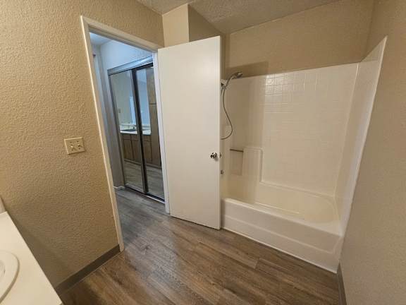 A white door is open to a bathroom with a white tub.