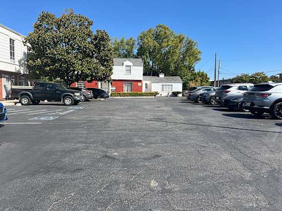A parking lot with cars and a white building in the background.