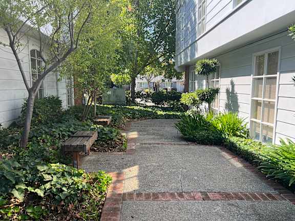 A white building with a tree and bench in front.