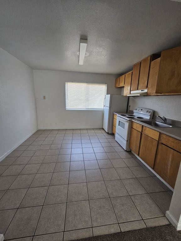 an empty kitchen with a stove refrigerator and sink