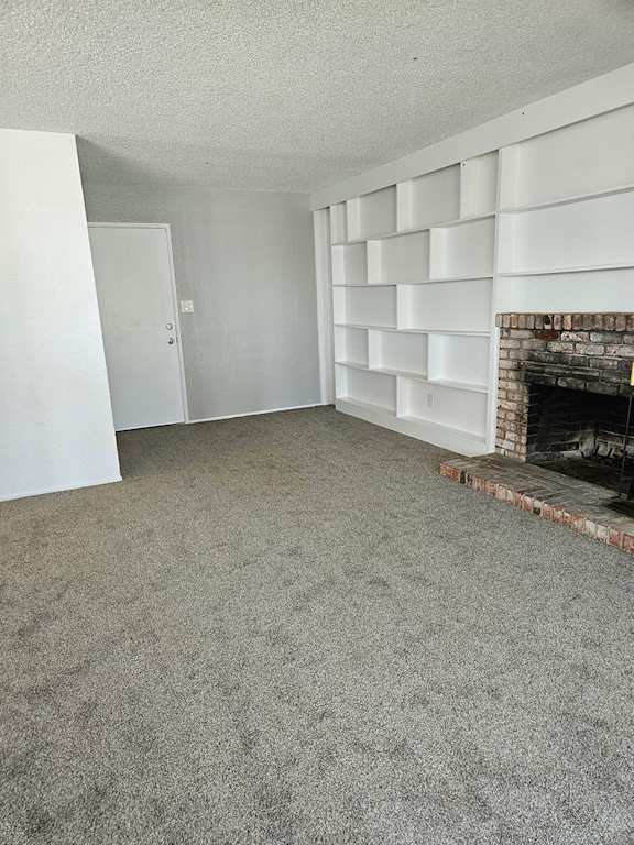 an empty living room with a fireplace and a carpeted floor