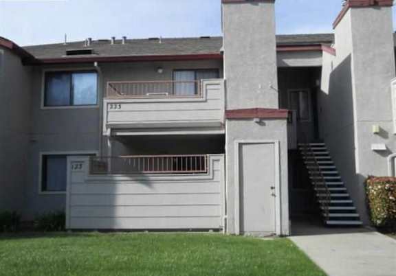 the front of a gray house with a white door