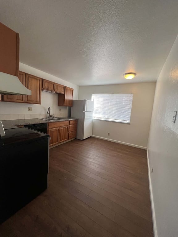 an empty kitchen with wooden floors and a refrigerator