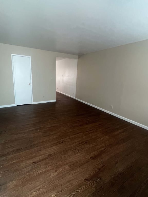 an empty living room with wooden floors and a white door