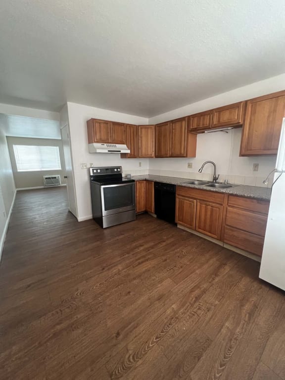 an empty kitchen with wood flooring and wooden cabinets