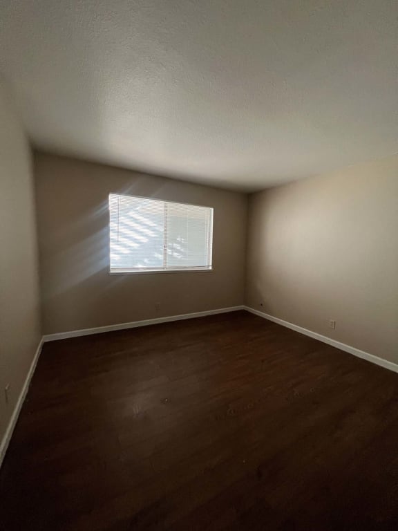 an empty room with wooden floors and a window