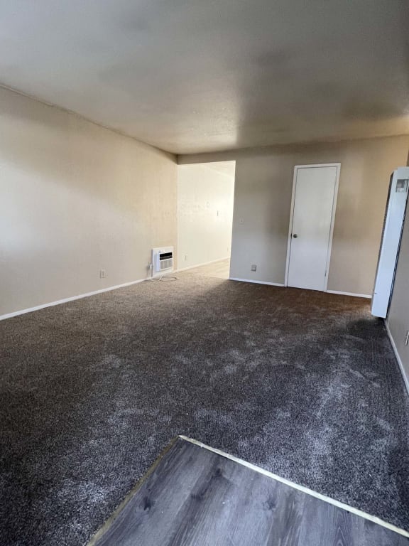 an empty living room with carpet and a door