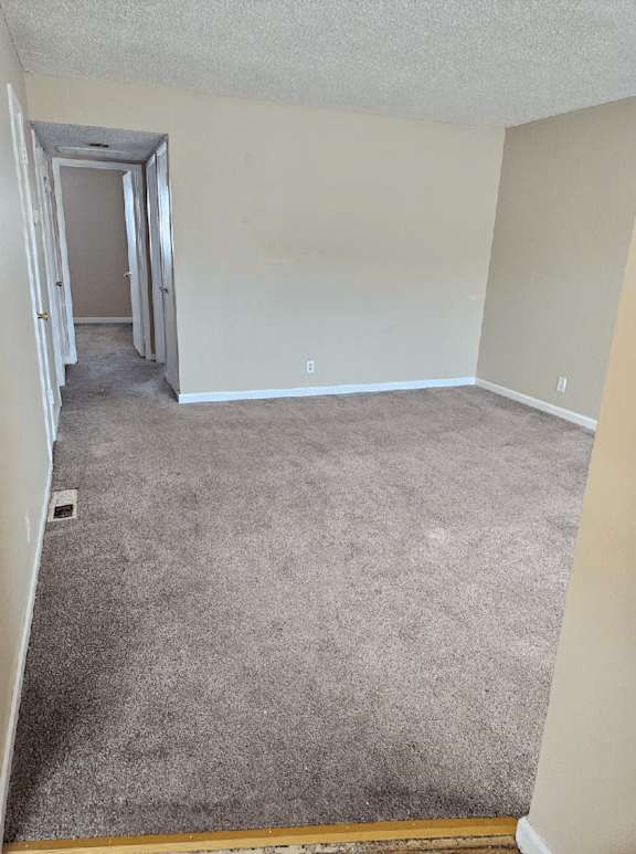 an empty room with a carpeted floor and a hallway