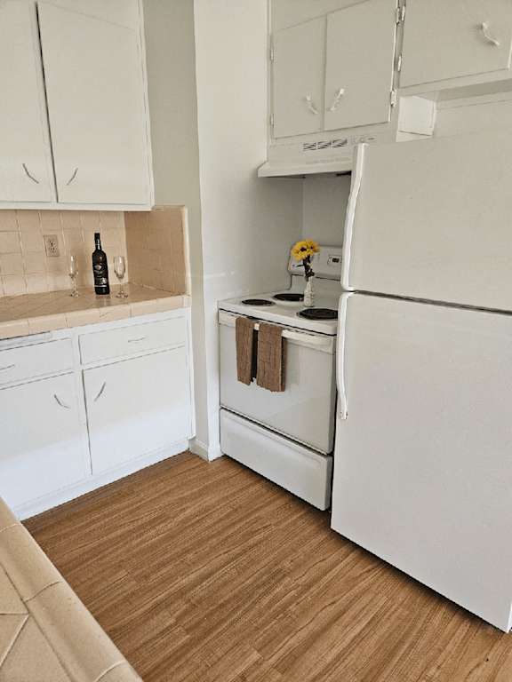 a kitchen with white appliances and a wooden floor