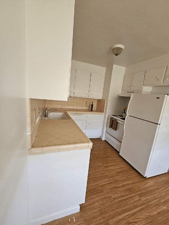 an empty kitchen with white cabinets and a refrigerator