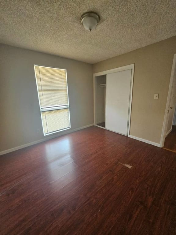 an empty living room with wood floors and a window