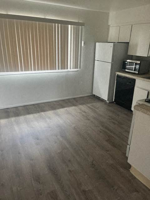 an empty kitchen with a refrigerator and a microwave