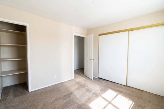 a bedroom with white walls and a closet and a door