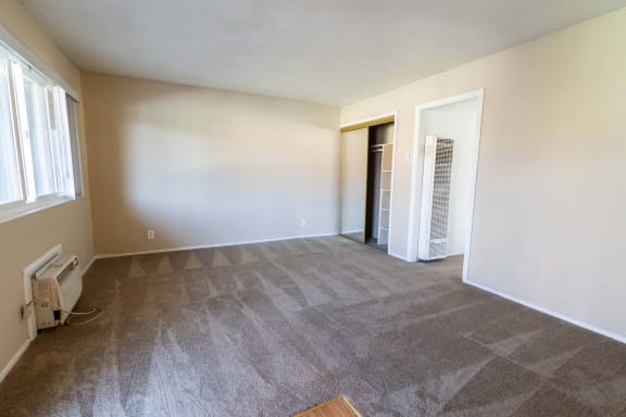 the living room and dining room of an empty home with white walls and carpet
