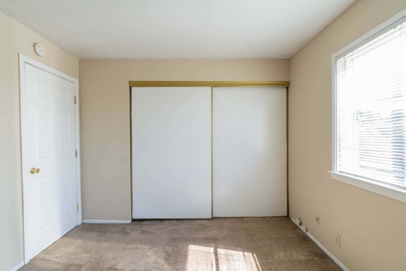 an empty room with white closet doors and a window