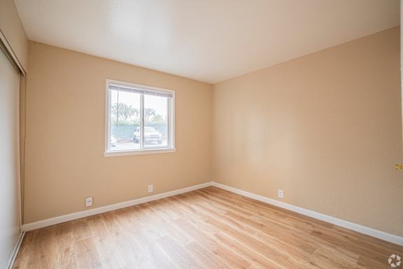 Empty room with a window and wooden flooring.