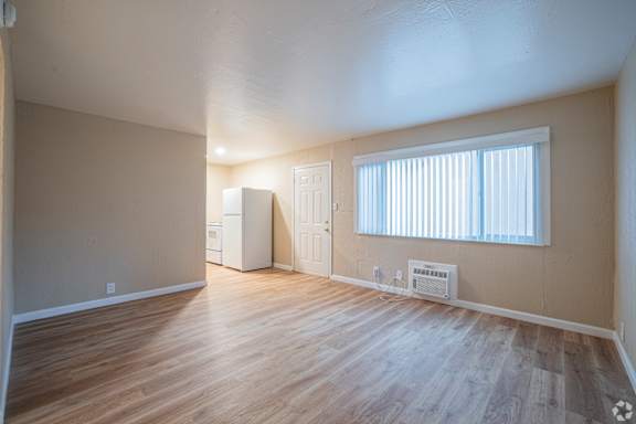 A room with wooden floors and a window with blinds.