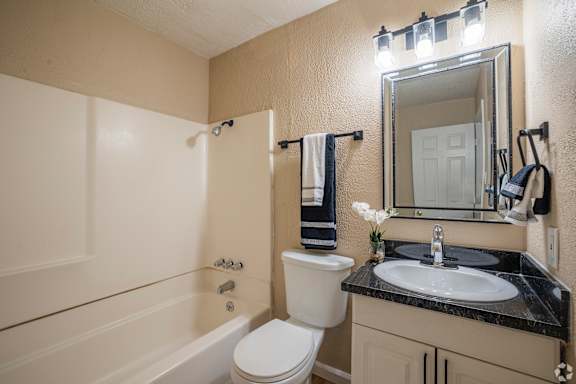 A bathroom with a toilet, sink, and mirror.