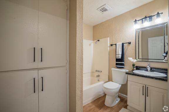 A white toilet sits in a bathroom next to a white sink.