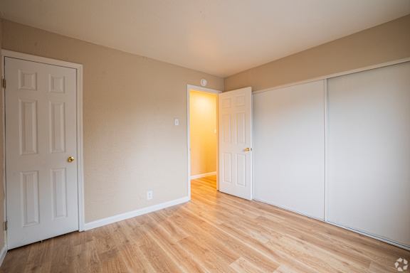 A room with a white door and a white wall with a light switch.