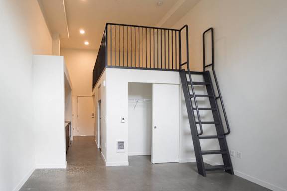 A black ladder is leaning against a white wall in a room with a white floor and a white ceiling.