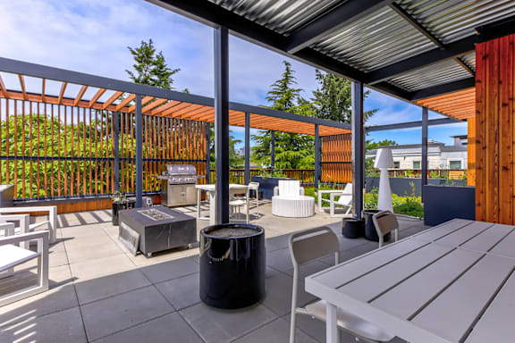 a patio with tables and chairs and a grill and glass doors
