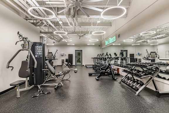A gym with a variety of equipment including treadmills, weights, and exercise machines.