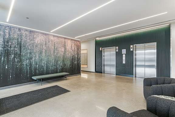 A room with a forest mural on the wall and a bench in front of it.