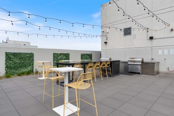a patio with tables and chairs and a barbecue grill