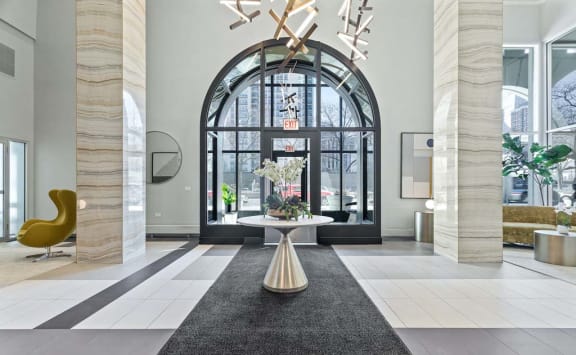 a lobby with a large glass door and a table with flowers