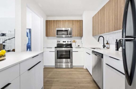 a white kitchen with stainless steel appliances and white counters