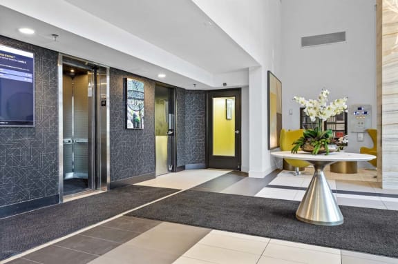 a lobby with two elevators and a table with flowers