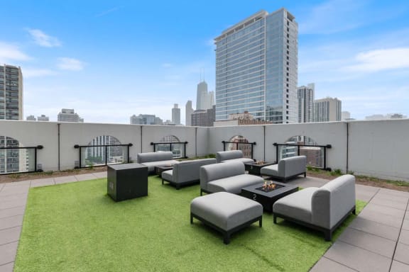 a rooftop patio with lounge furniture and a view of the city