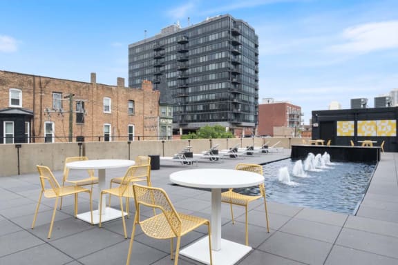 a rooftop patio with tables and chairs and a fountain