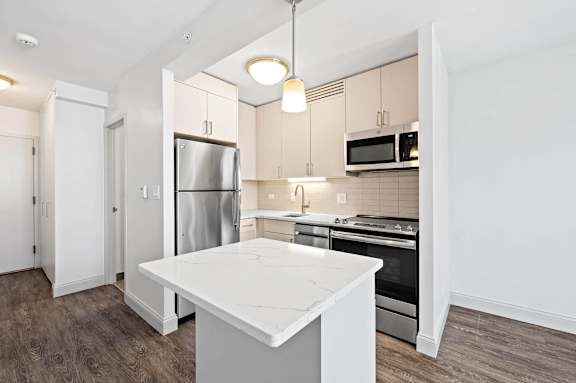 A kitchen with a white island and stainless steel appliances.